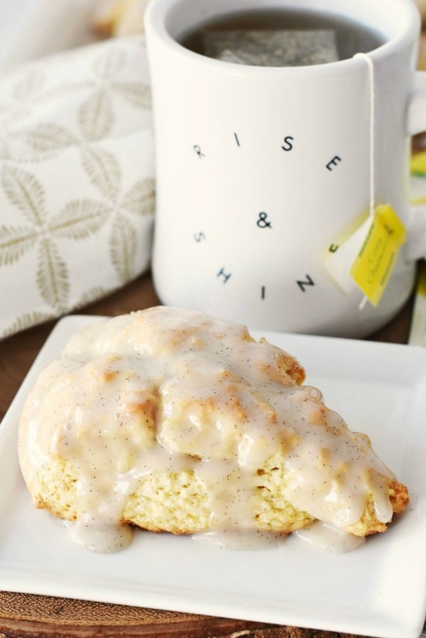 A Rise and Shine mug with tea and a vanilla scone.