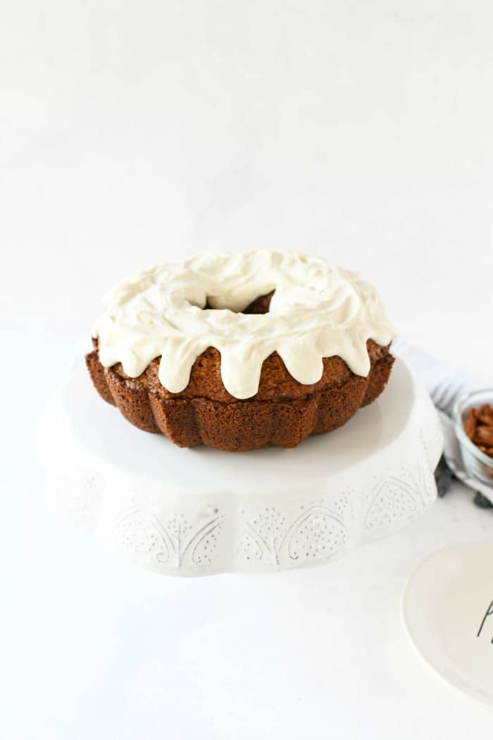 Frosted Carrot Cake on white cake stand.