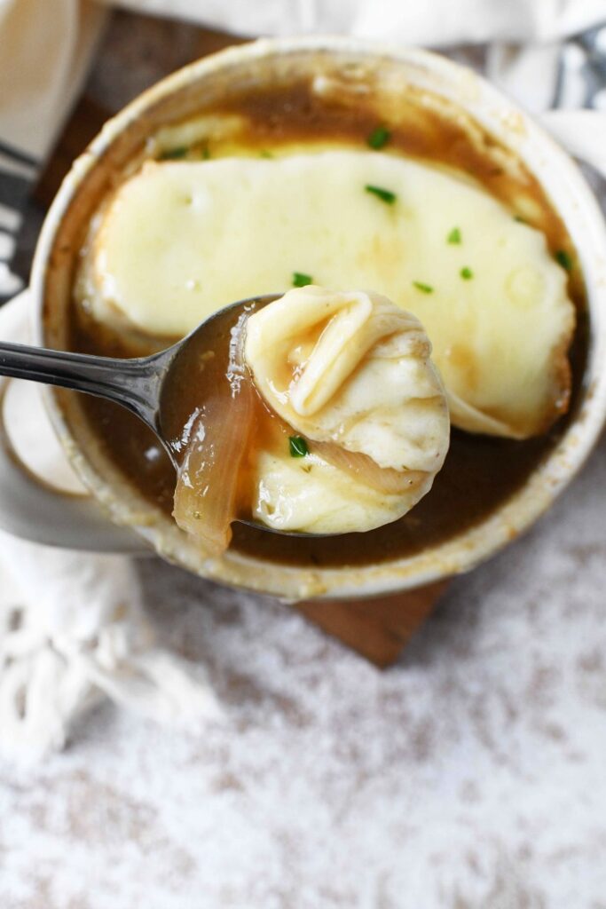French onion soup with sherry in spoon.