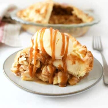 Apple pie with ice cream and caramel drizzled on top with ice cream.