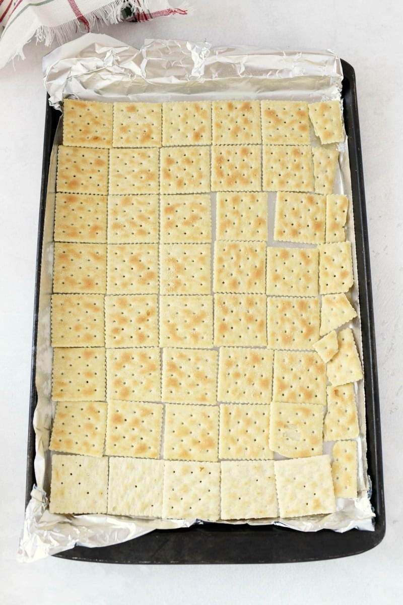 saltine crackers lined on a aluminum foil pan.