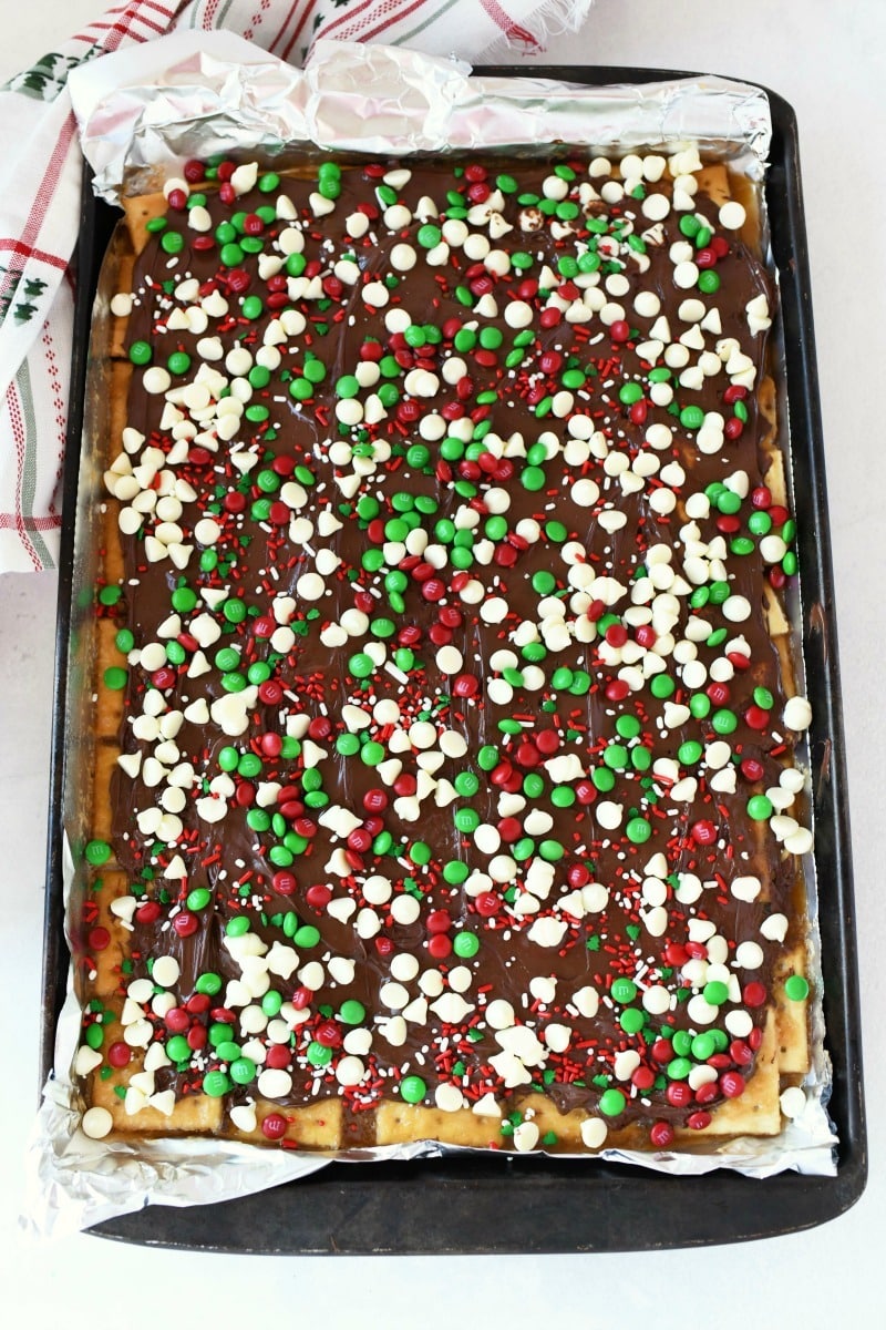 Chocolate covered saltines in a jelly roll pan. The bars have Christmas sprinkles on them.