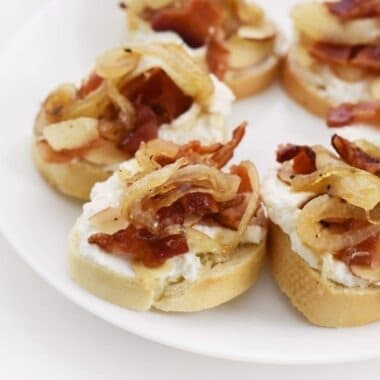 Caramelized Bacon Bites on a white plate with white paper napkins.