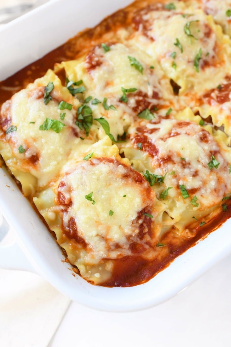 Lasagna Roll Up recipe. A roll up is on shown up close in a white casserole dish.