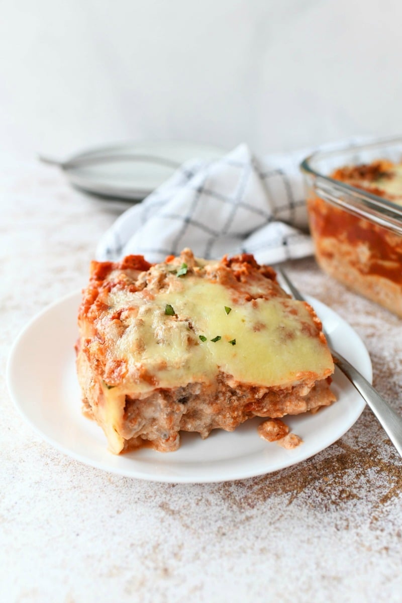 Meat and Cheese Lasagna Slice on a white small dish with a silver fork. 