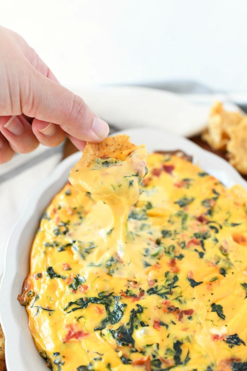cheesy spinach bacon dip on a chip. The dip is hot and gooey. 