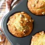 Baked Jumbo Banana Nut Muffins baked in a black muffin tin. There is a pink floral napkin nearby.