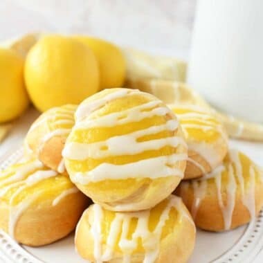 Lemon Crescent Danish stacked on a white platter with fresh lemons.