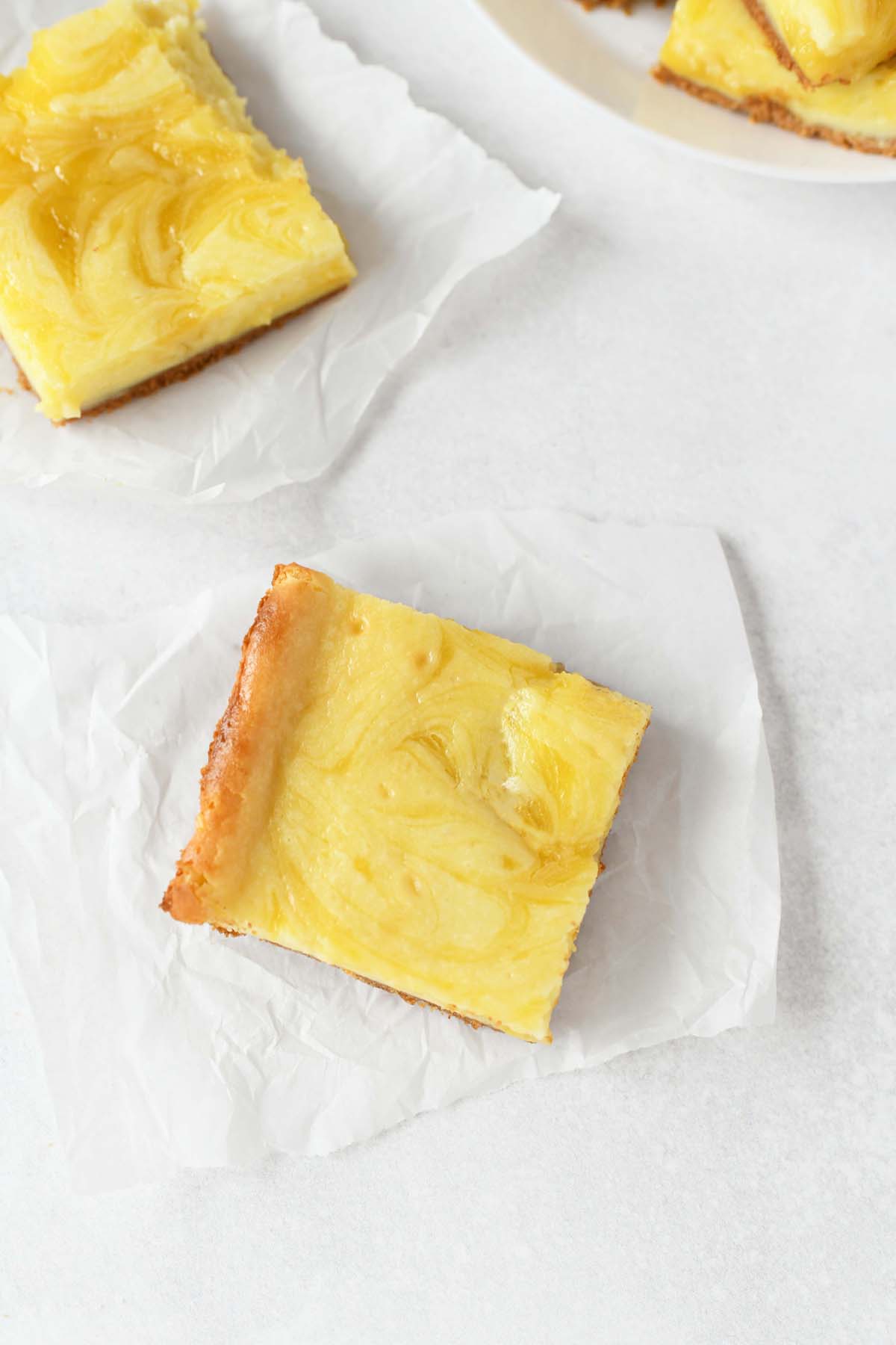 Lemon Swirled Cheesecake cut and on pieces of white parchment paper.