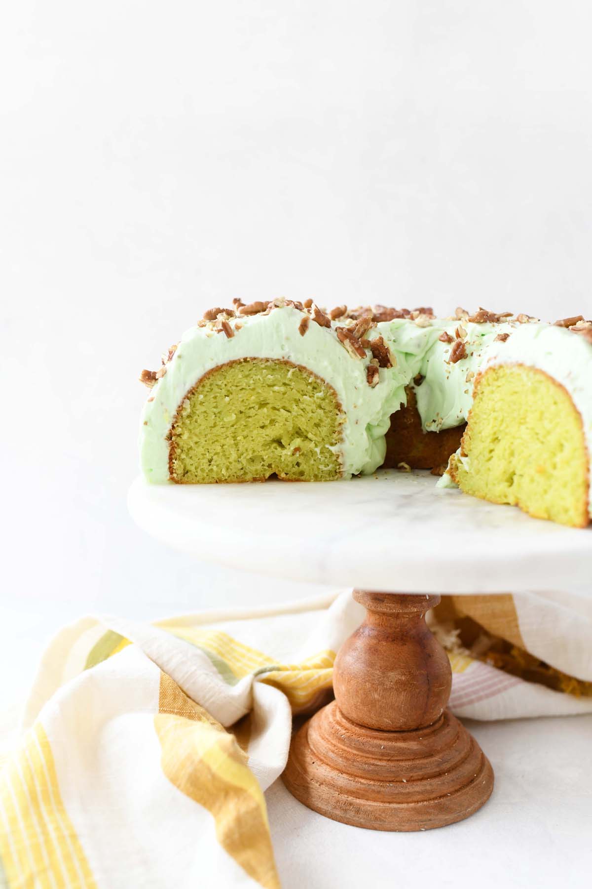 Pistachio Dream Cake sliced on a white marble cake stand.