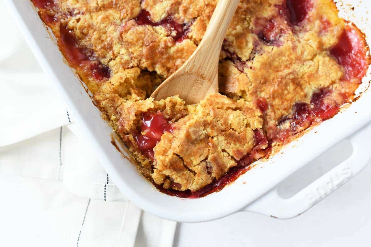 Cherry dump cake in a wooden spoon.