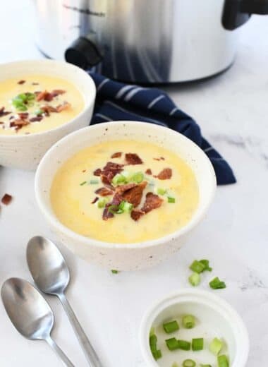 Cheesy potato soup in a bowl with silver spoons.