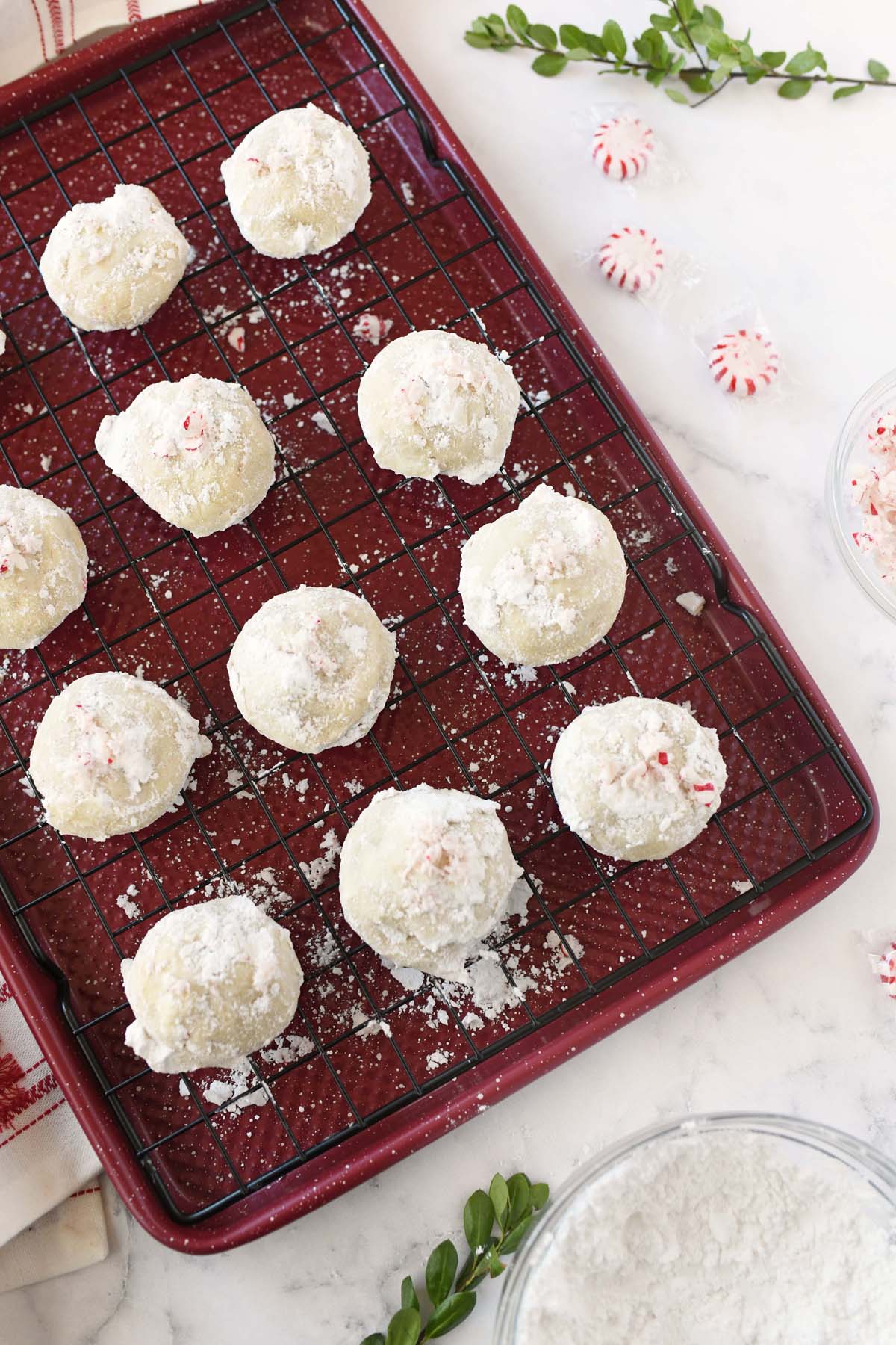 Peppermint snowball cookies on a red baking tray,