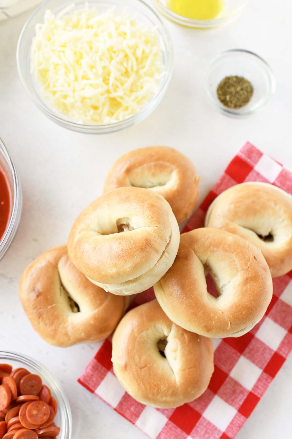 Bagels on a red checkered napkin with toppings.