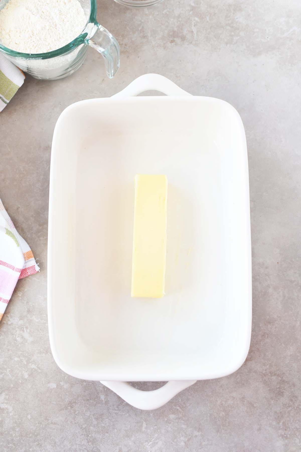 A stick of butter in a white baking dish.