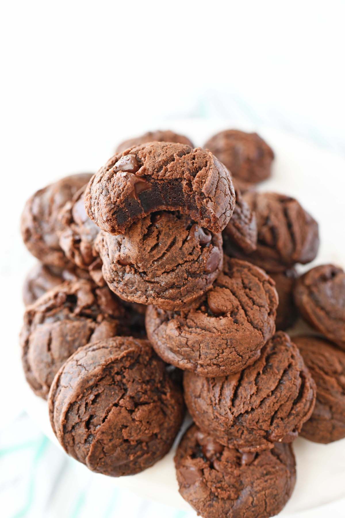 Chewy fudge brownie cookies with a bite taken out of one, stacked.