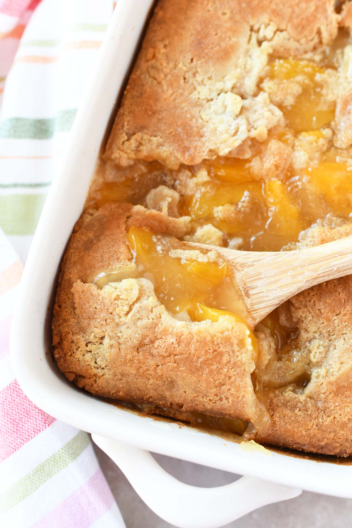 Peach cobbler with a wooden spoon.