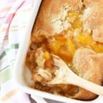 Peach cobbler on a wooden spoon.