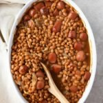 hot dogs and beans casserole in white oval dish.