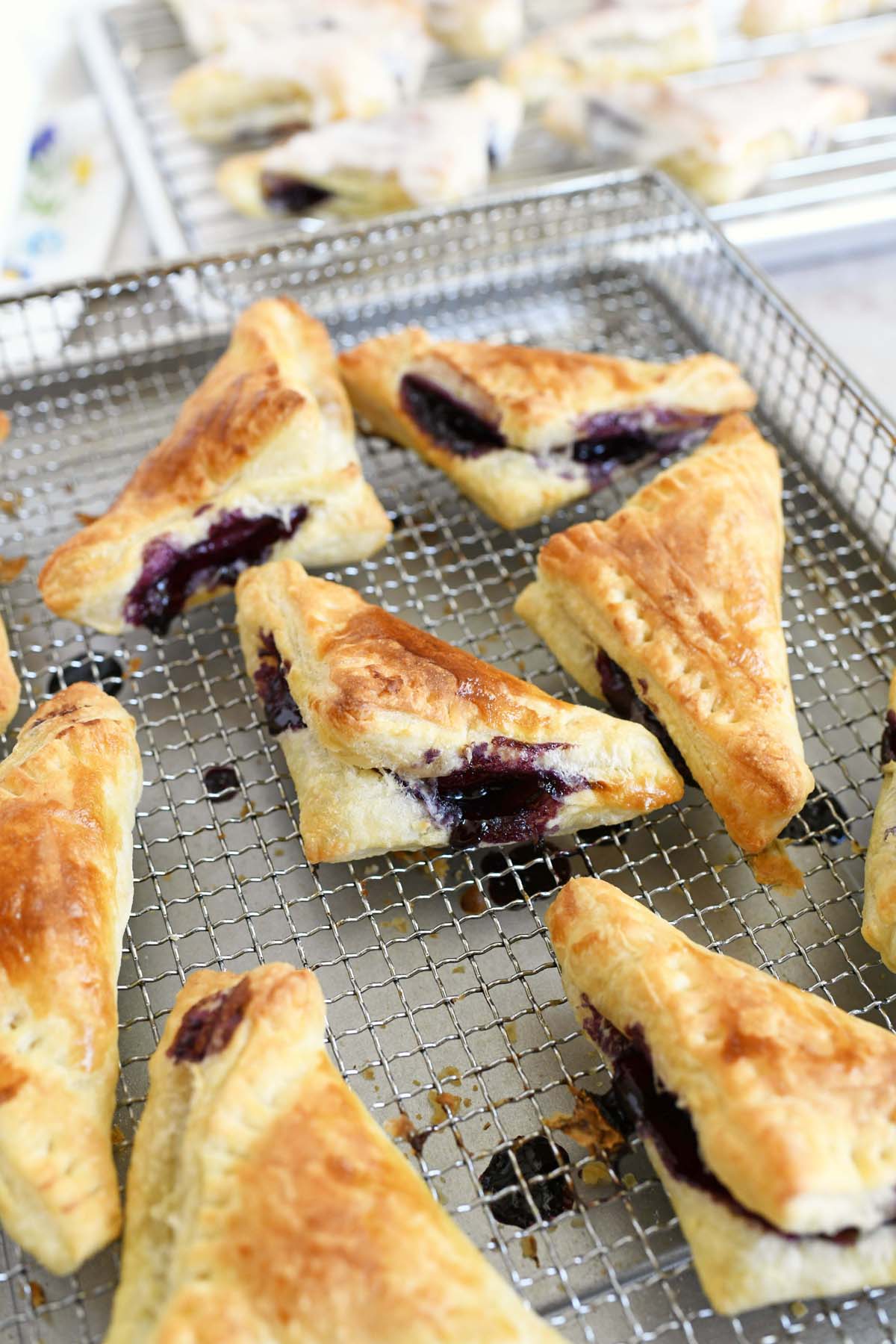 Golden browned mini blueberry turnovers on an air fryer tray.