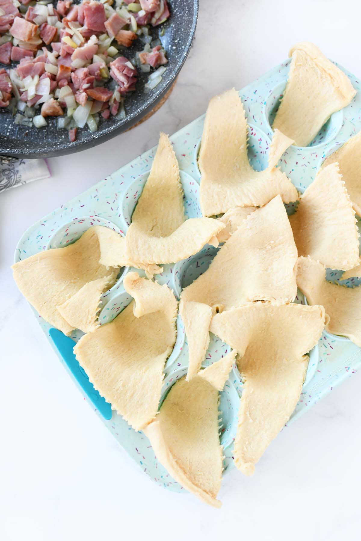 Crescents dough triangles  in a blue muffin tin. 