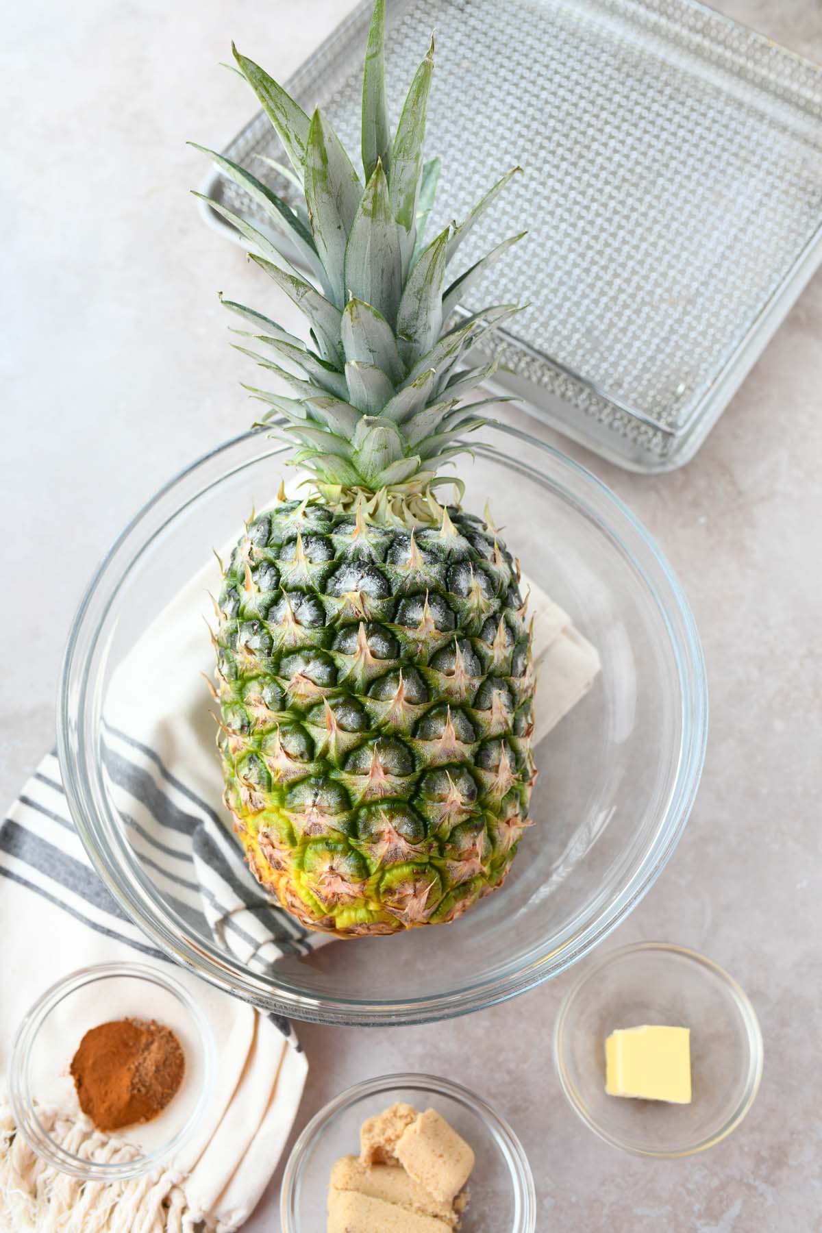 Whole pineapple in a glass bowl with spices. 
