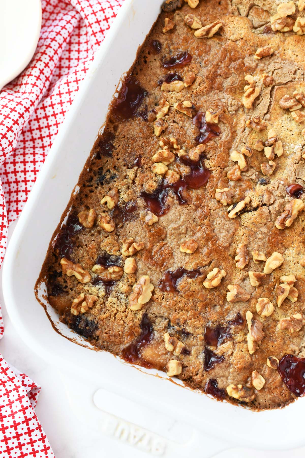 Cranberry Apple Dump cake with walnuts on it in a white pan.