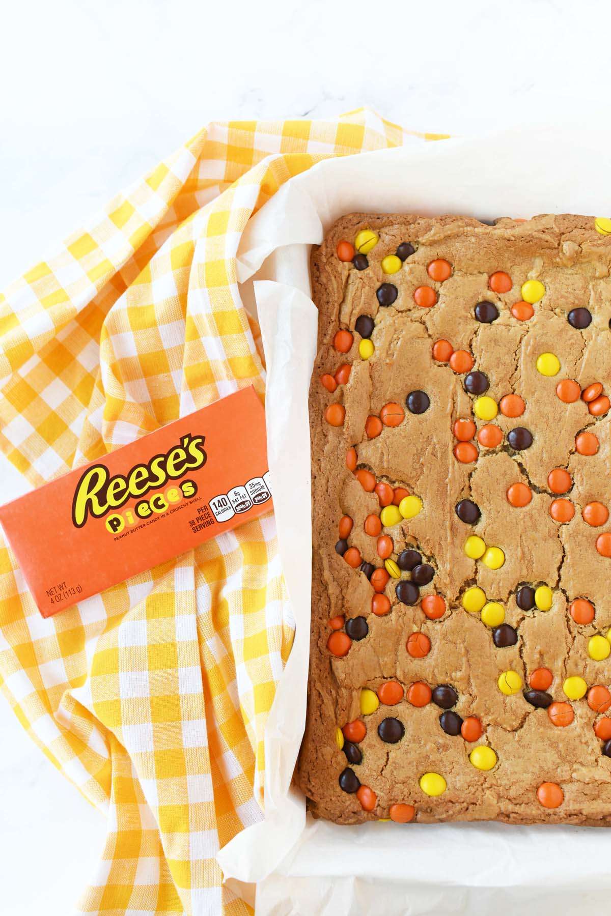 Reese's Pieces brownies near a yellow napkin and candy box.