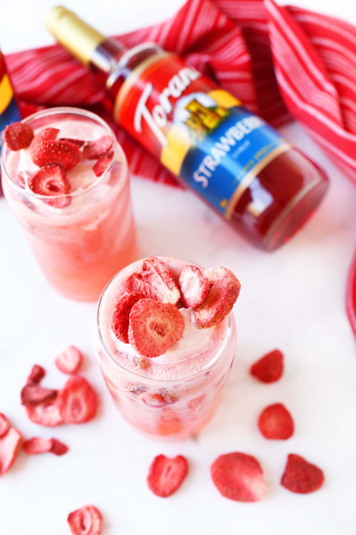 A pink drink filled with freeze dried strawberries.
