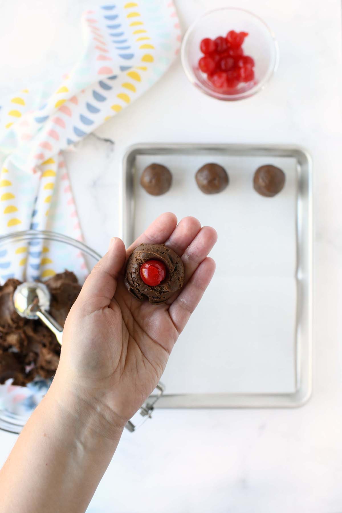 A white hand holding a cherry brownie truffles inside of it.