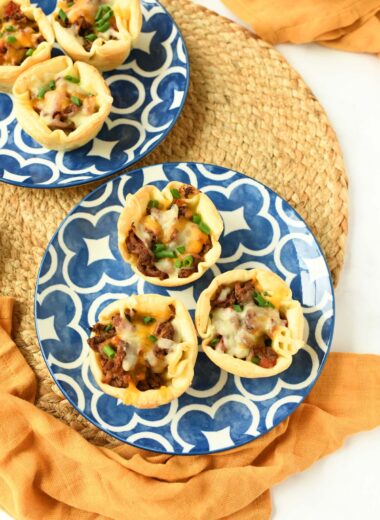 Empanada cups on blue plates with yellow napkins.