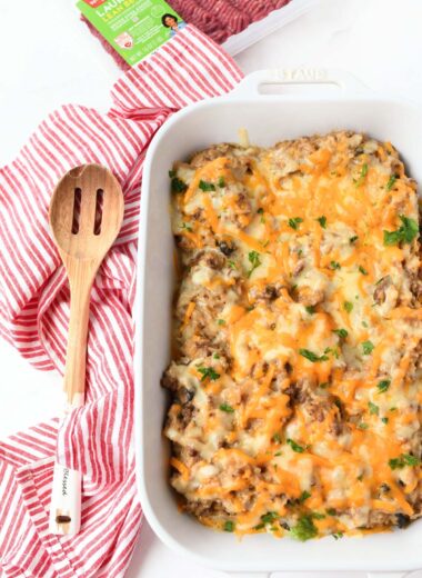 A white baking dish with cheesy, beefy rice casserole.