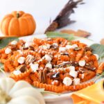 Loaded sweet potato fries with marshmallow, pecans, and drizzle with mini pumpkins nearby.