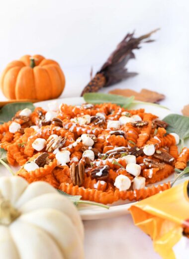Loaded sweet potato fries with marshmallow, pecans, and drizzle with mini pumpkins nearby.