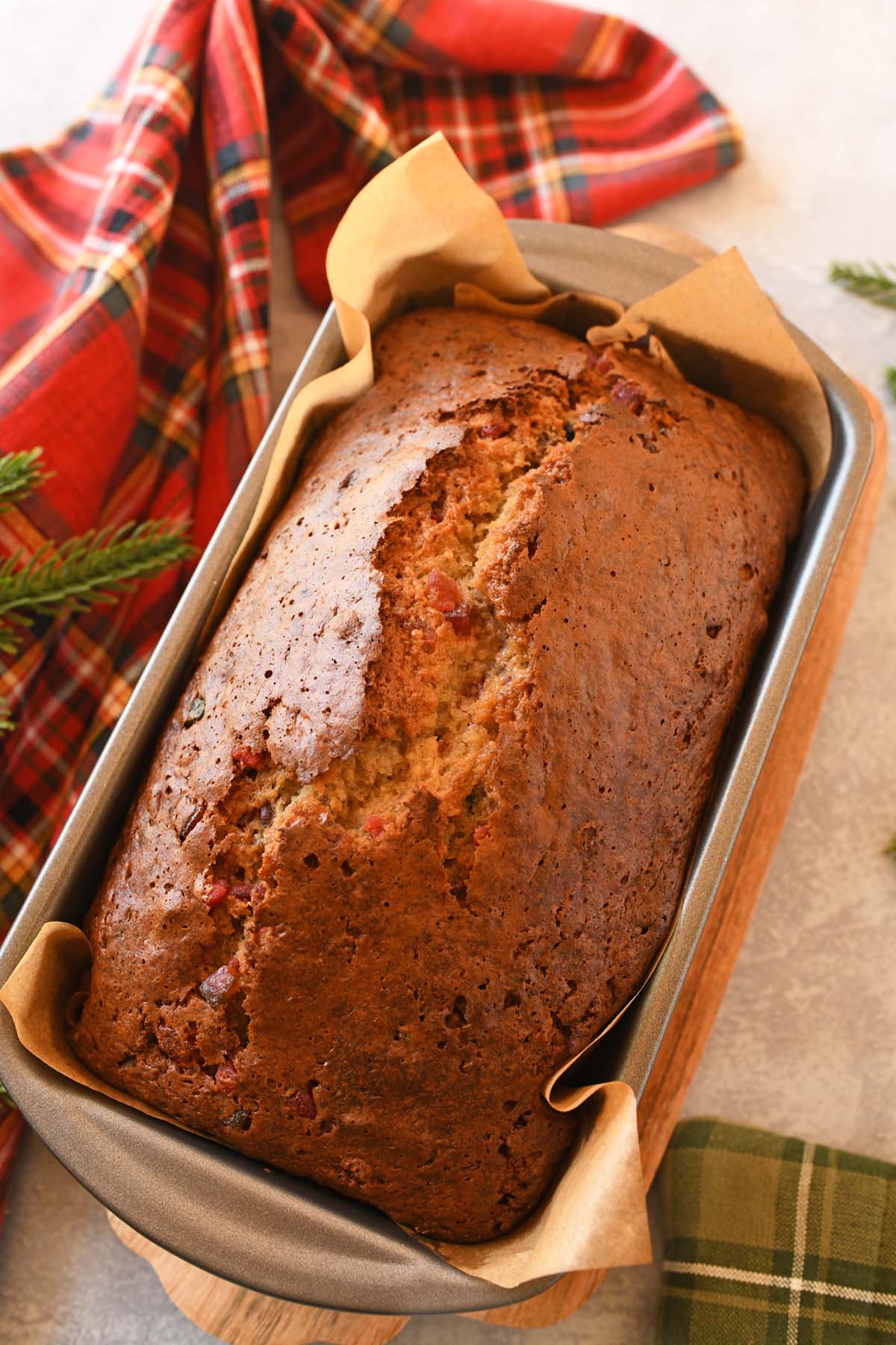 Slice of baked banana fruitcake near a red, flannel napkin.