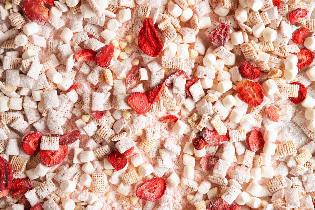 Up close shot of pink coated rice cereal with mini mallows, freeze dried berries, and white chocolate chips.