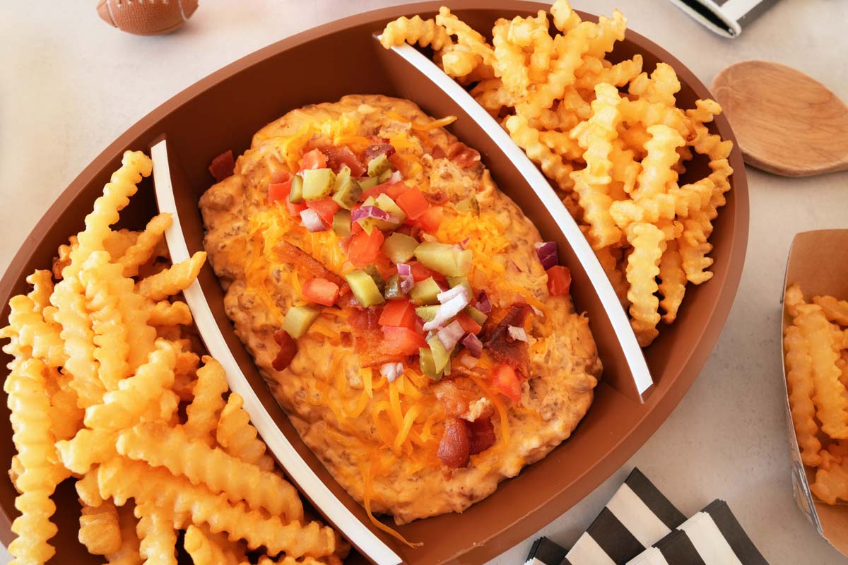 An upclose shot of cheeseburger dip with McCain Crinkle Cut fries in a football bowl.