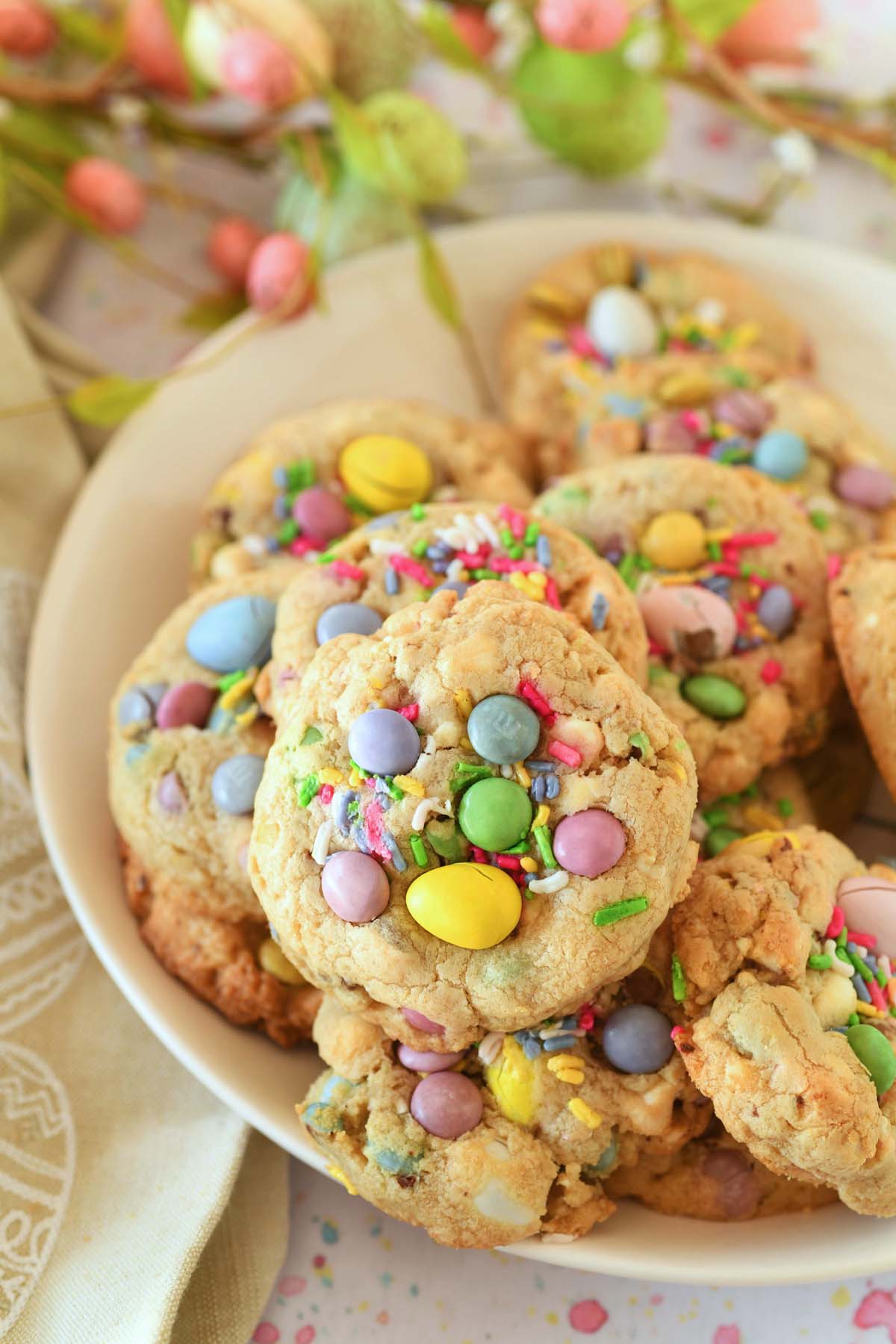 Up close shot of pastel Easter candy cookies on a white plate on an Easter-themed table setting.