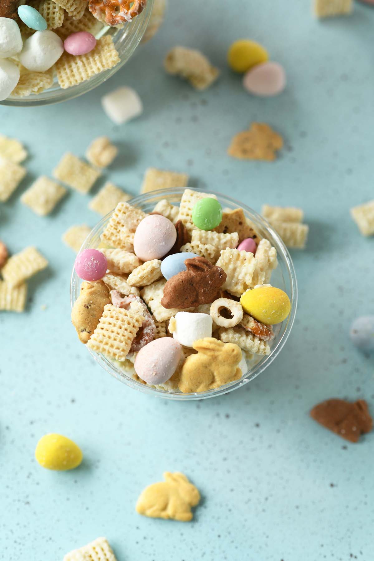 Top-down view of Easter Bunny Bait in a cup and scattered on a blue surface, showing a blend of salty and sweet ingredients.