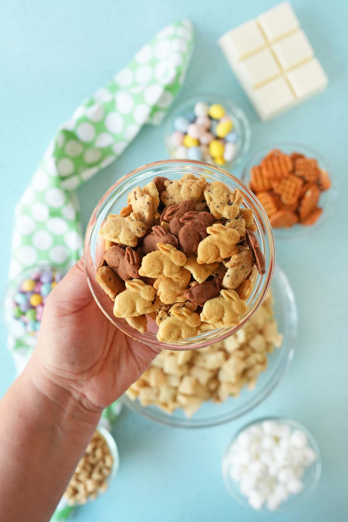 A hand holding up a glass bowl of bunny graham crackers.