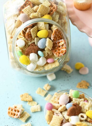 A clear glass jar filled with bunny bait with some spilled onto a blue table.