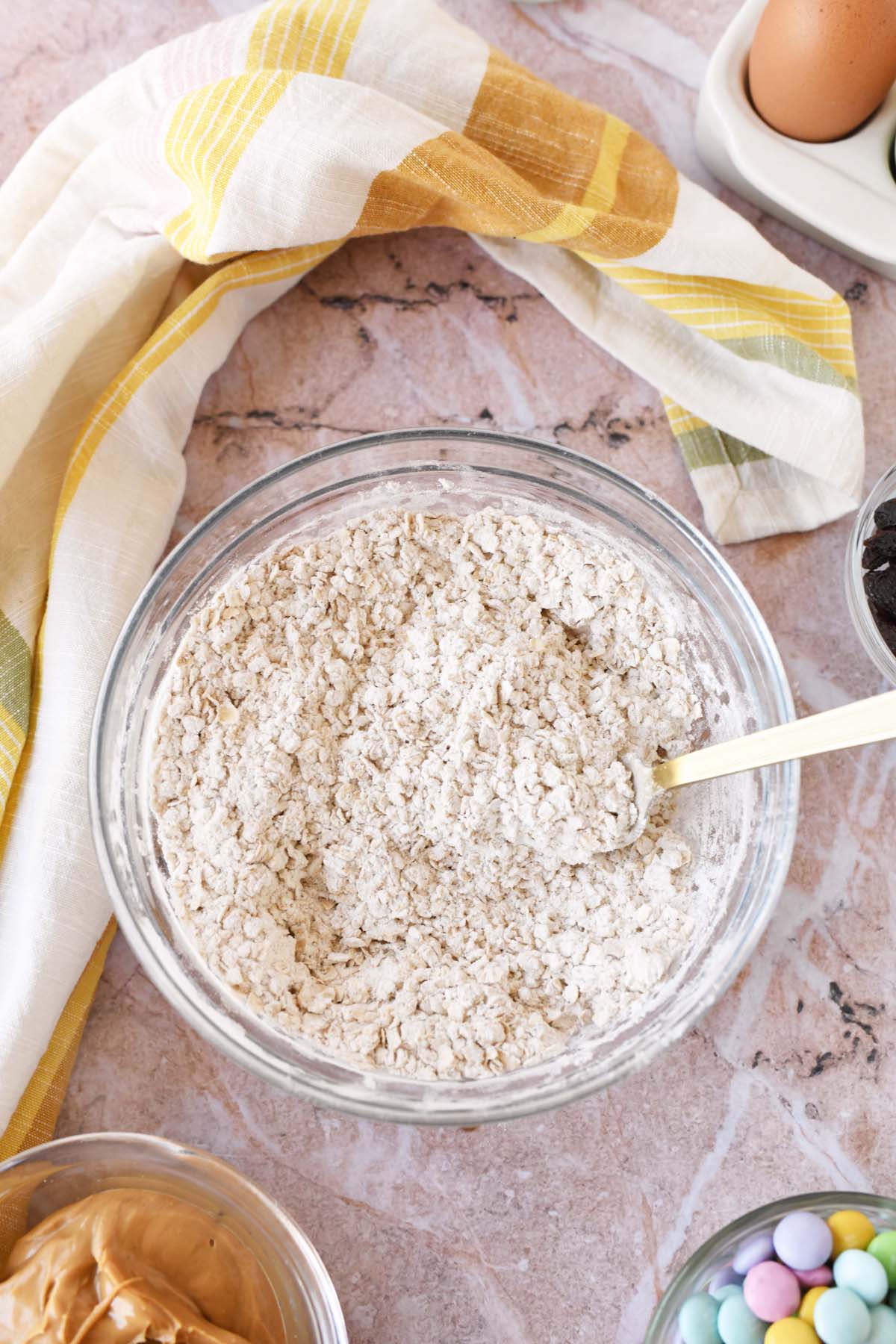 Oats a flour in a glass mixing bowl with a striped napkin nearby.