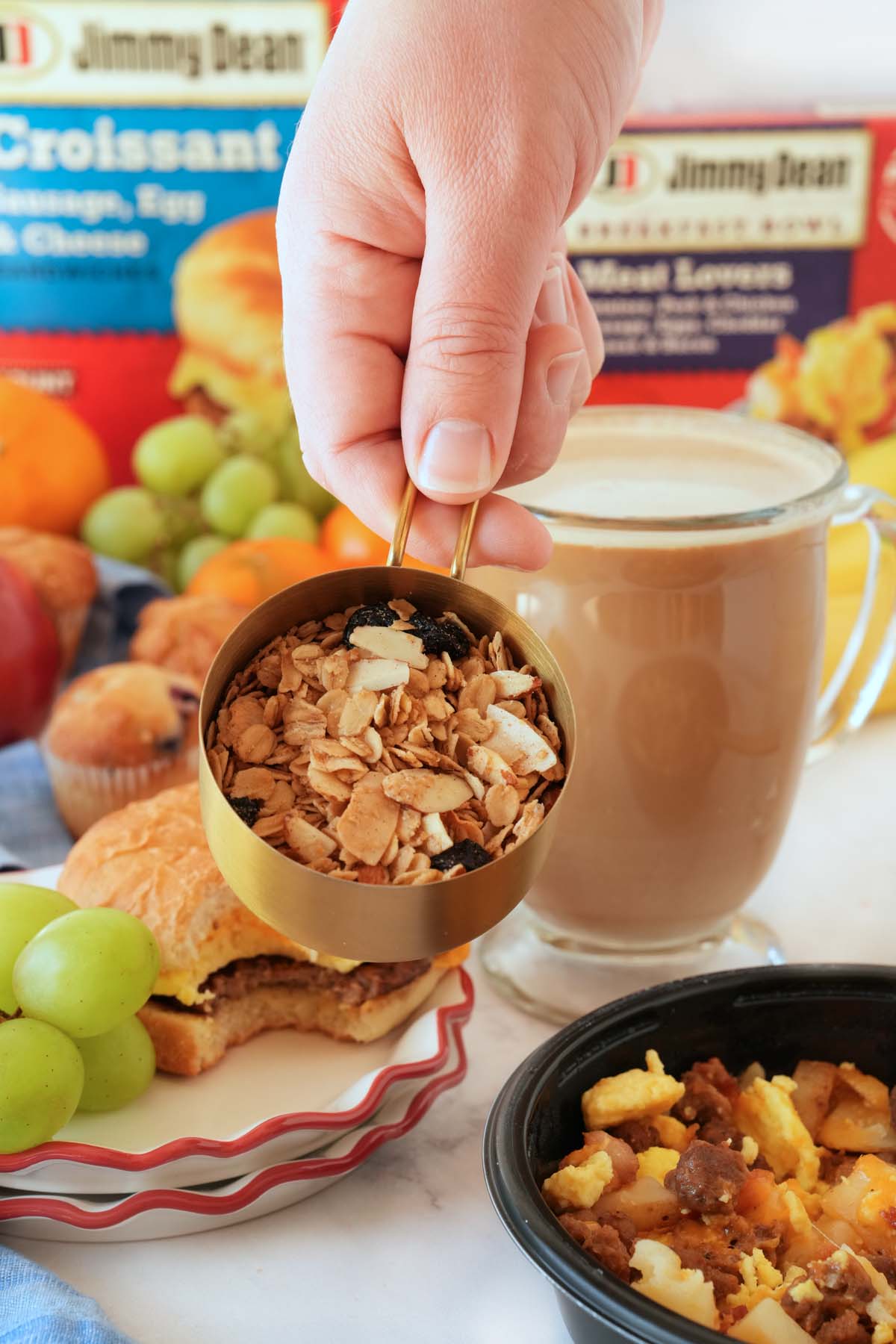 A scoop of Granola in a hand up close near other breakfast foods.
