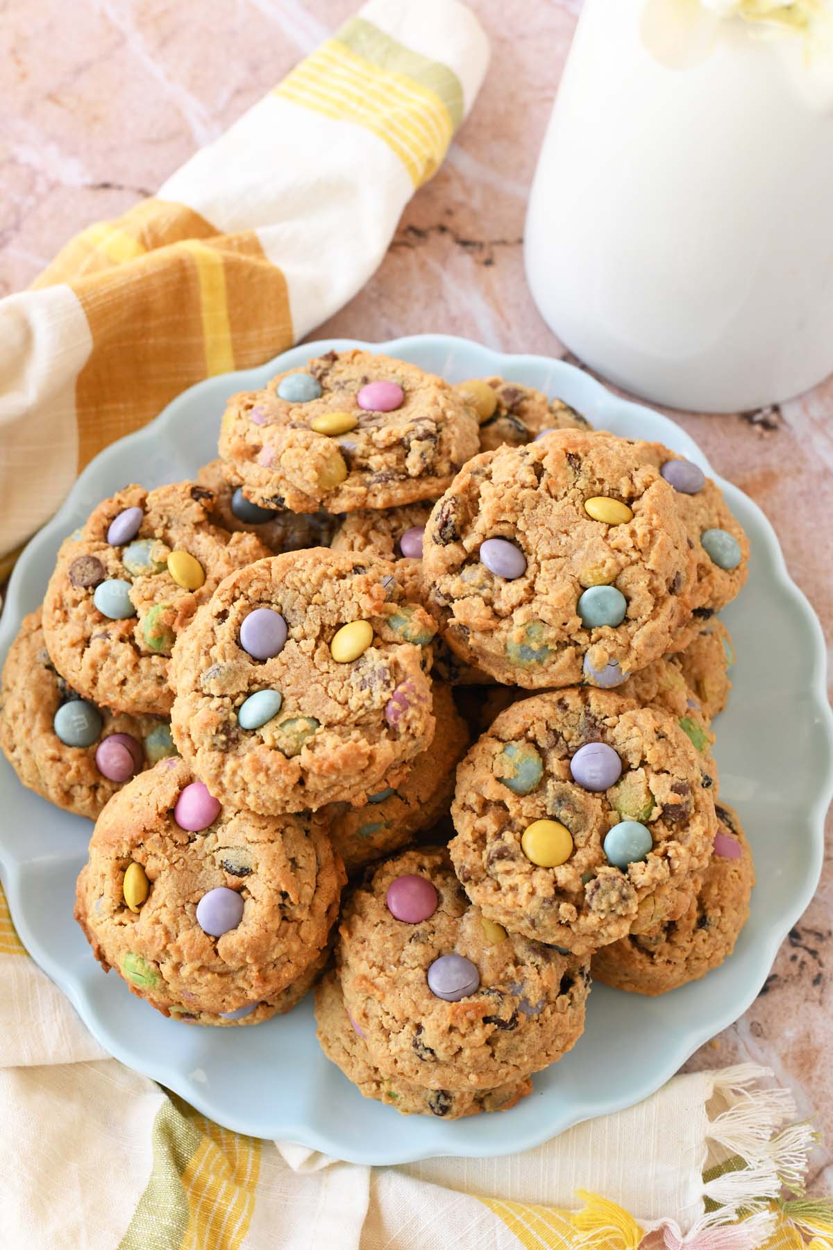 A plate of pastel monster cookies on a blue plate near a striped napkin.