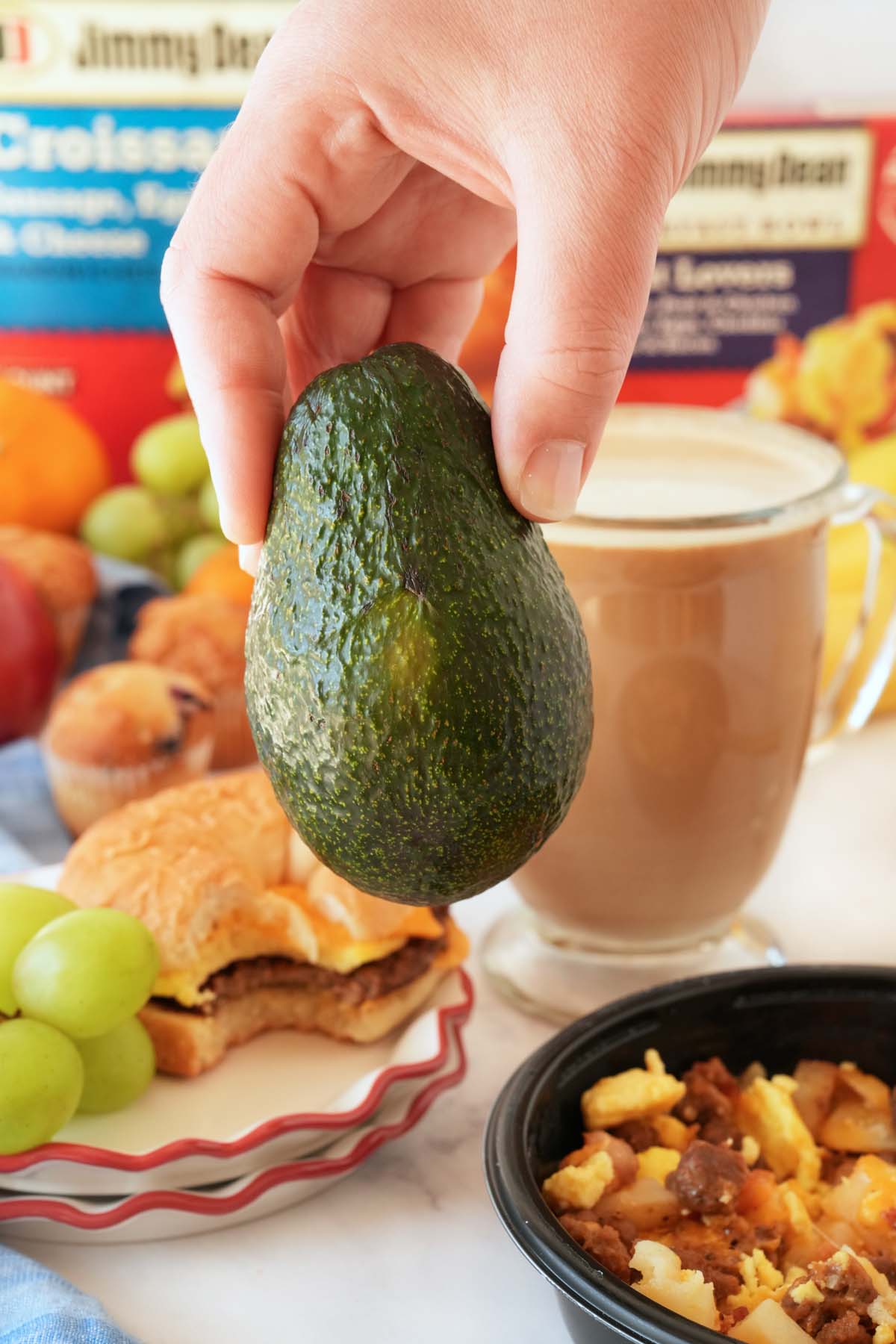 A hand holding a green avocado close up.