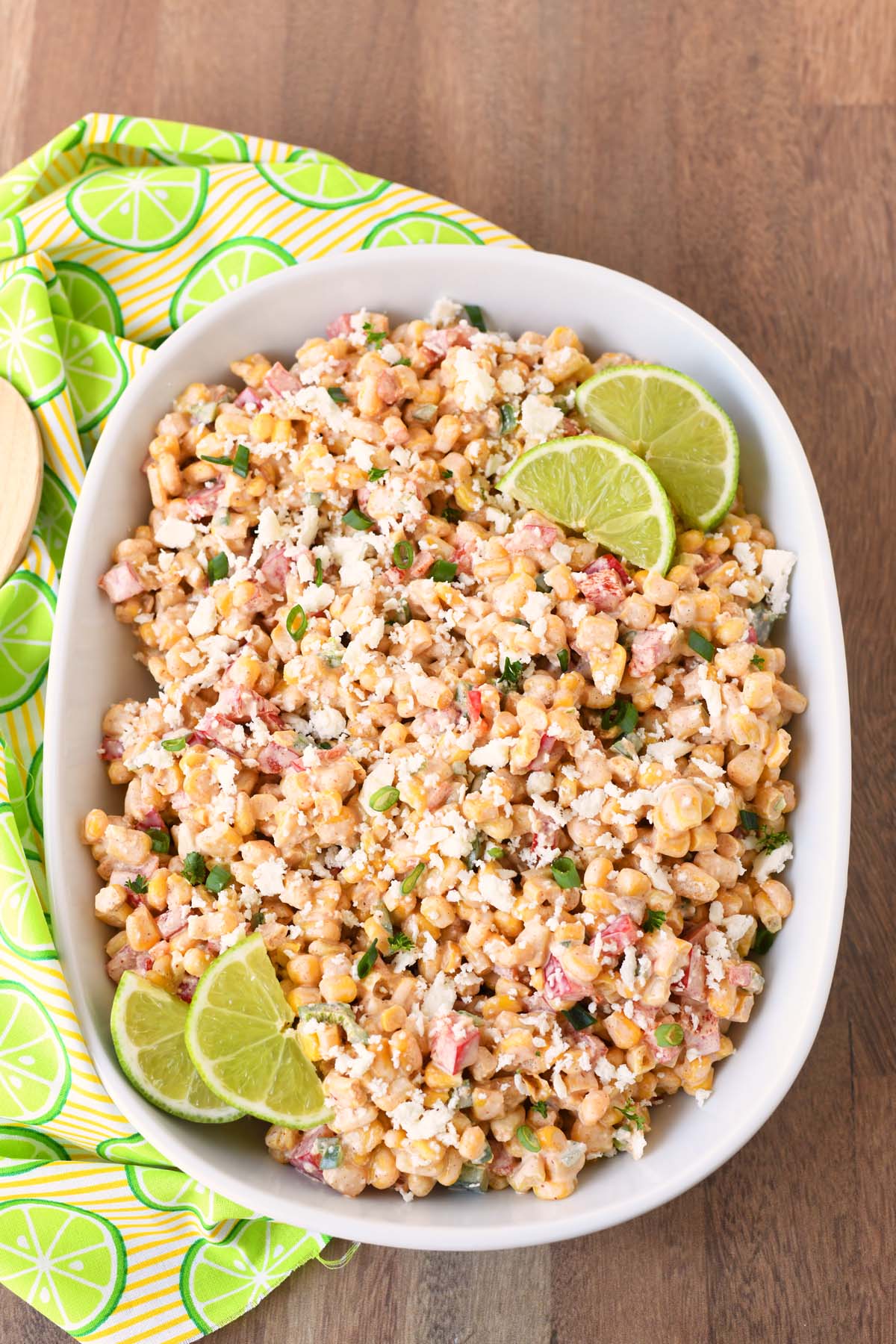 Chipotle corn salad with limes on a wooden table with a lime napkin.