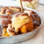 A gold fork with peach bun cobbler on it.