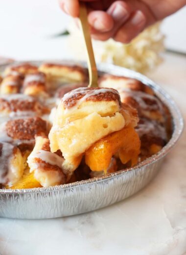 A gold fork with peach bun cobbler on it.
