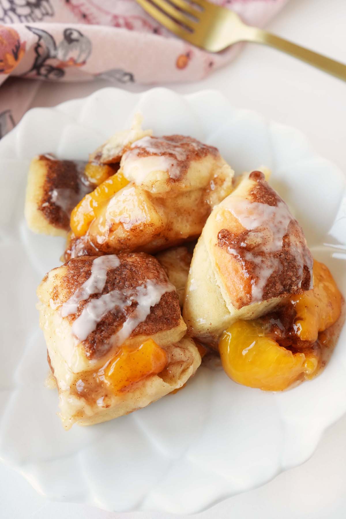 Up close shot of cinnamon and sugar peach buns on a white plate.