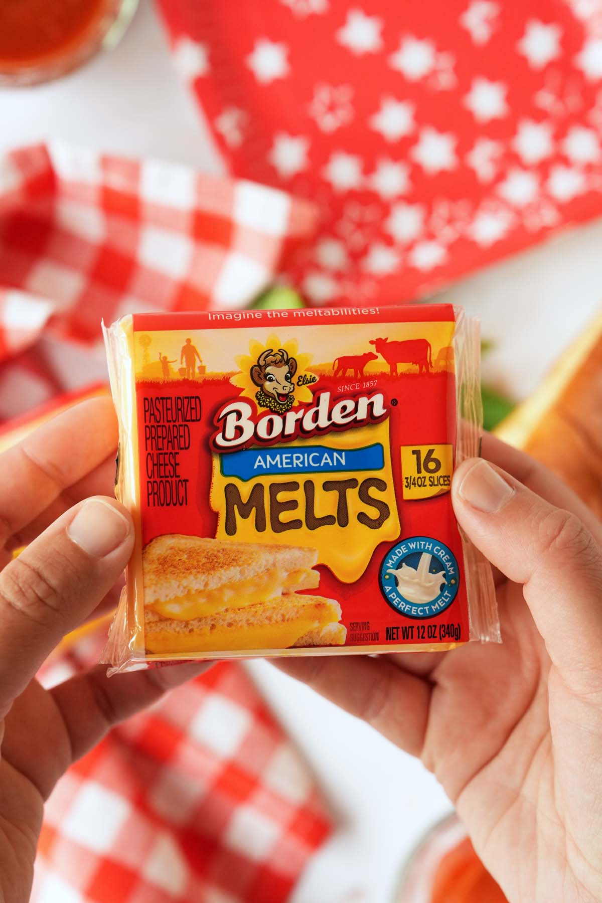 Borden American melts package in-hands with red, patterned napkins and plates nearby.